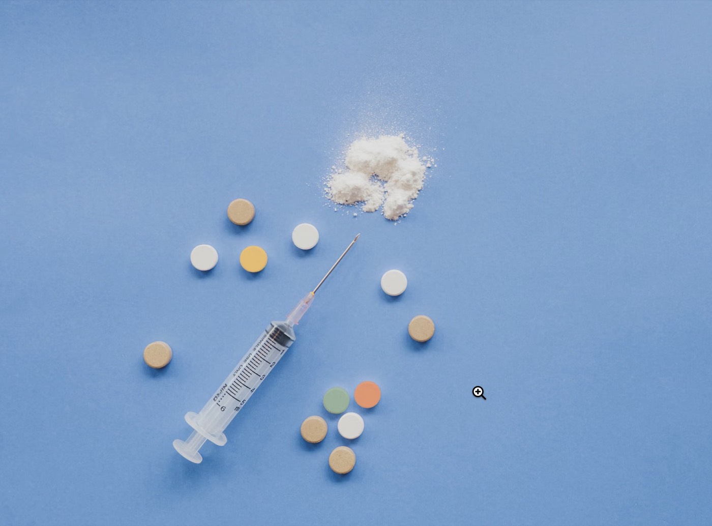 Comprimés colorés et seringue disposés côte à côte, illustrant le choix entre voie orale et voie injectable